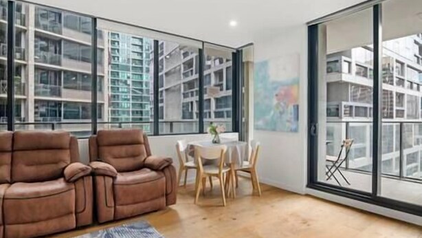 Un salon moderne comprenant un canapé, une table à manger avec des chaises et de grandes fenêtres donnant sur un paysage urbain.