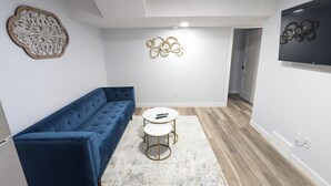 A modern living room with a blue sofa, a round coffee table, and a patterned rug.