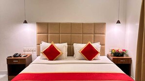 A modern hotel room with a large bed, two bedside tables, a telephone, and a nightstand. - YAM HOTEL  (Thiruvananthapuram)