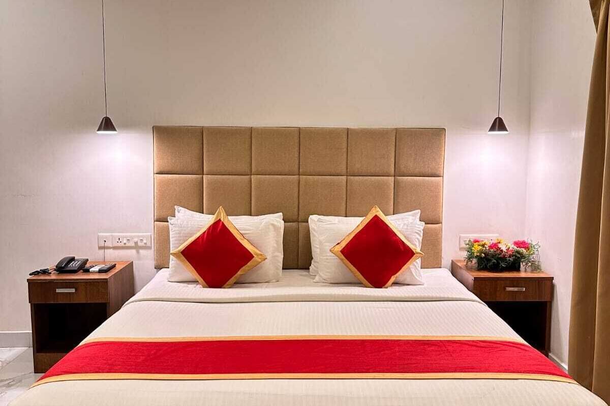 A modern hotel room with a large bed, two bedside tables, a telephone, and a nightstand.