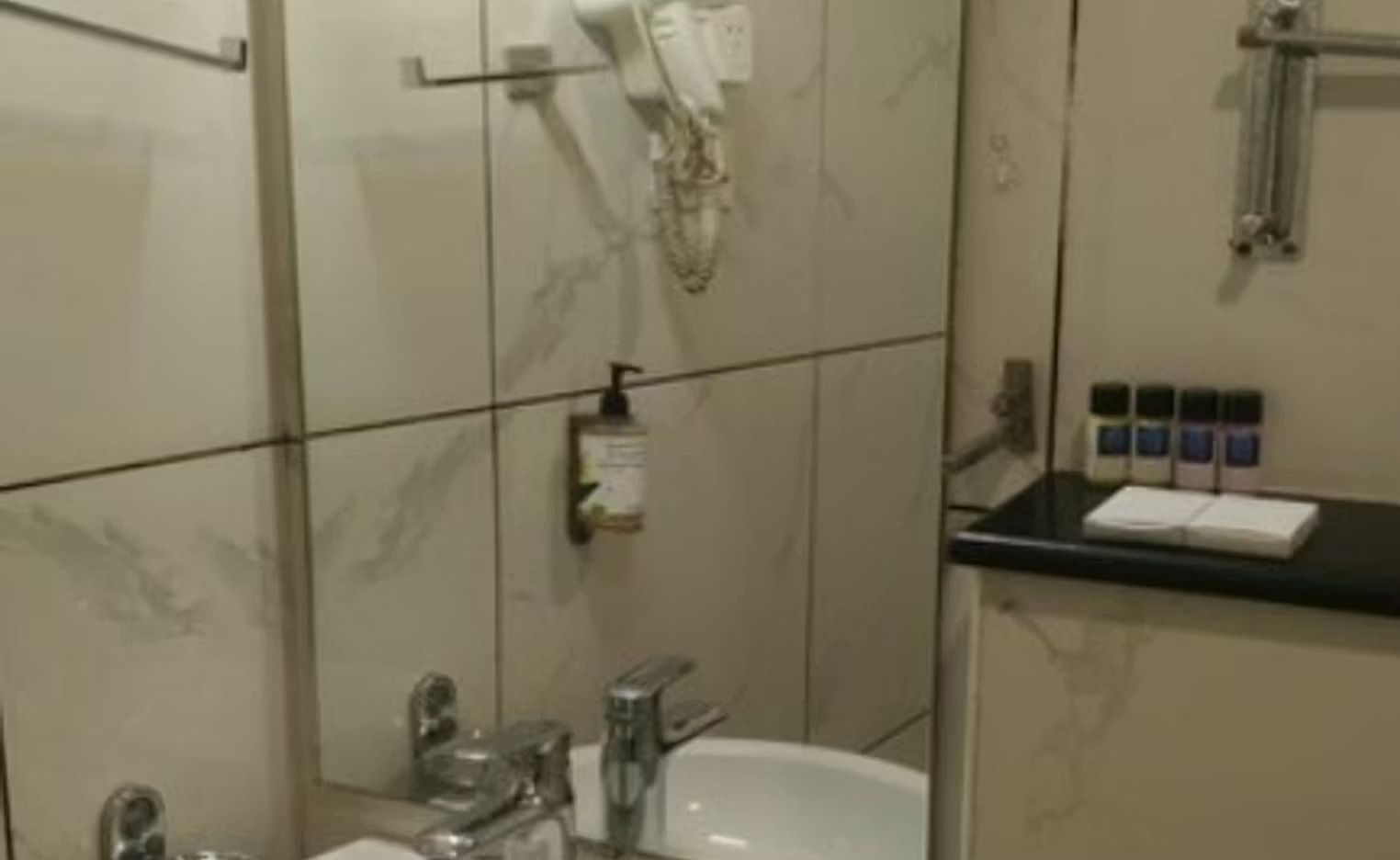 A bathroom with a bathtub, a sink, and a mirror. There are toiletries on a shelf.