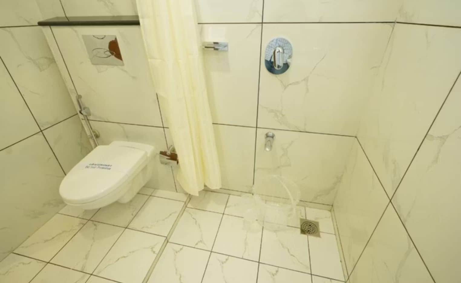 Ein Badezimmer mit Toilette, Dusche und Fliesenboden.