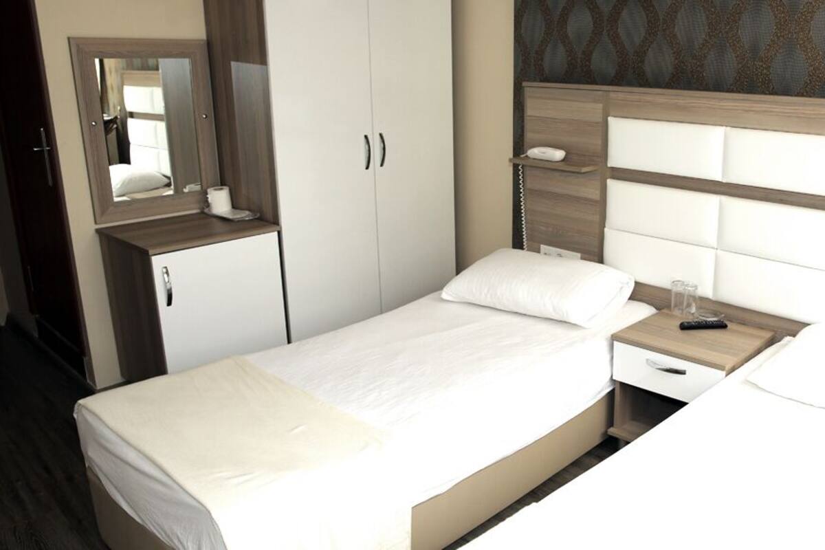 Une chambre d’hôtel comprenant un lit, une table de chevet, une commode et une armoire.