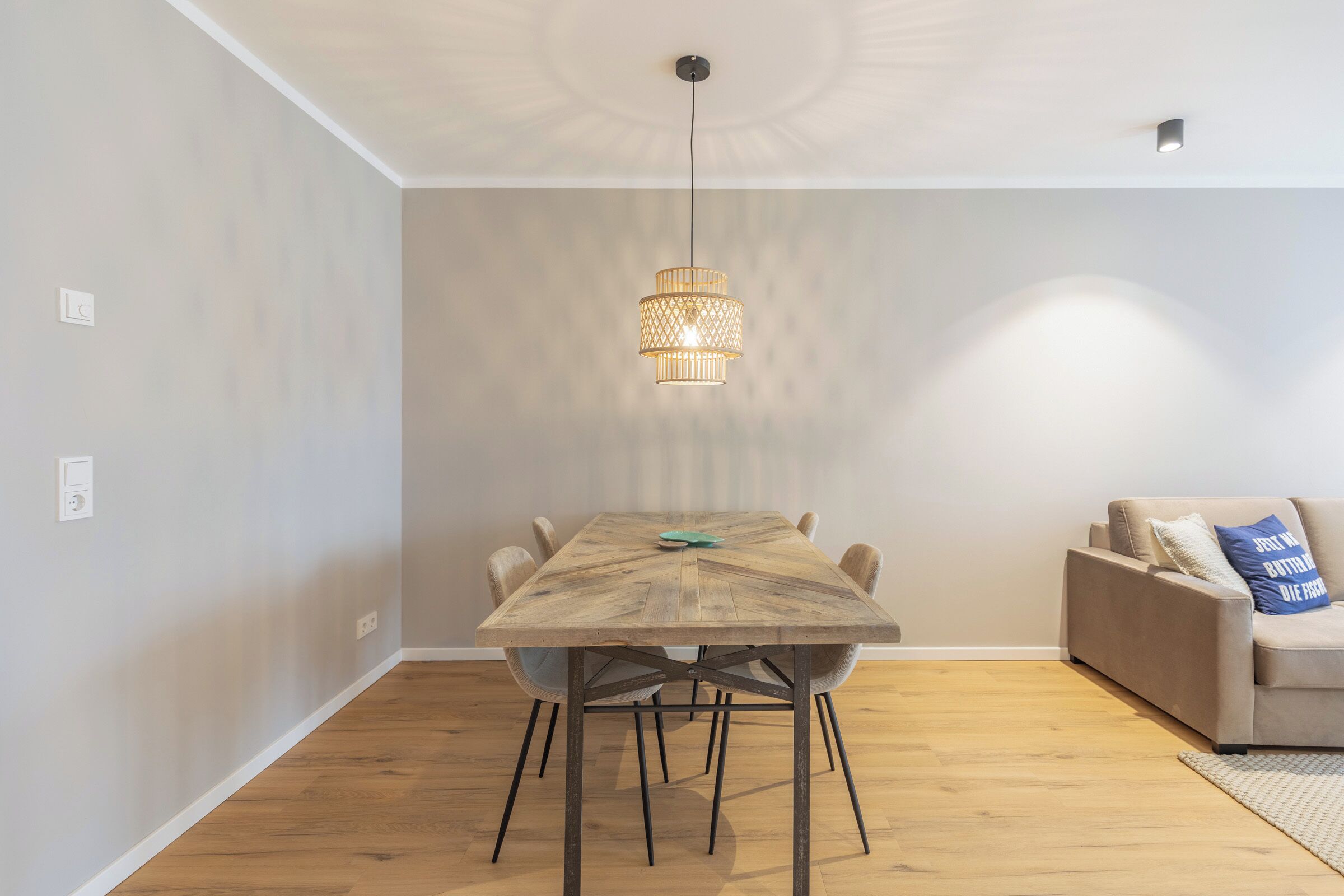 Een eetruimte met een houten tafel, stoelen en een hanglamp.