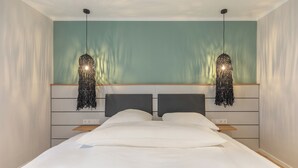 A bedroom with a bed, two bedside tables, a headboard, and two hanging lights. - Deluxe apartment Zollbude 02 directly at Husum harbor (Husum)
