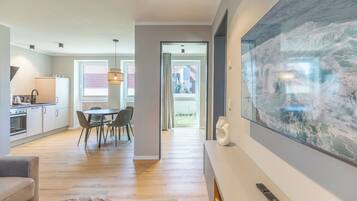 A modern kitchen with a dining area, a large artwork, and a remote control on a table.