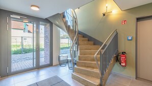 A modern interior with a spiral staircase, a fire extinguisher, and a glass door leading outside. - Apartment at the old customs office (Deluxe) directly at Husum harbor (Husum)