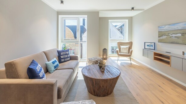 A modern living room with a sofa, coffee table, and TV. - Apartment at the old customs office (Deluxe) directly at Husum harbor (Husum)