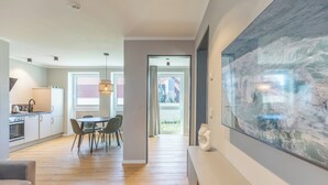 A modern kitchen with a dining area, a large artwork, and a remote control on a table. - Apartment at the old customs office (Deluxe) directly at Husum harbor (Husum)