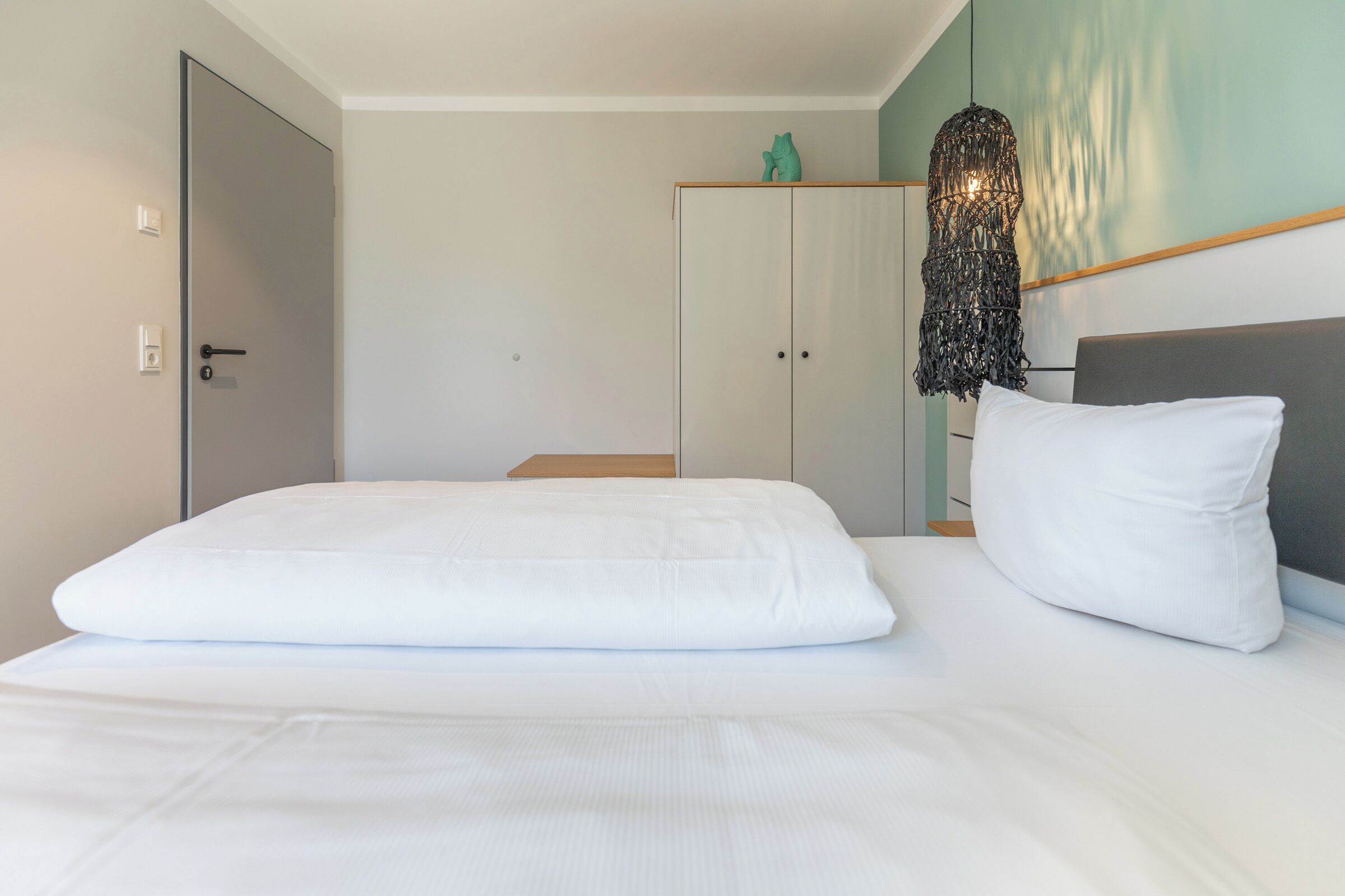 A bedroom with a bed, a wardrobe, and a hanging light fixture.