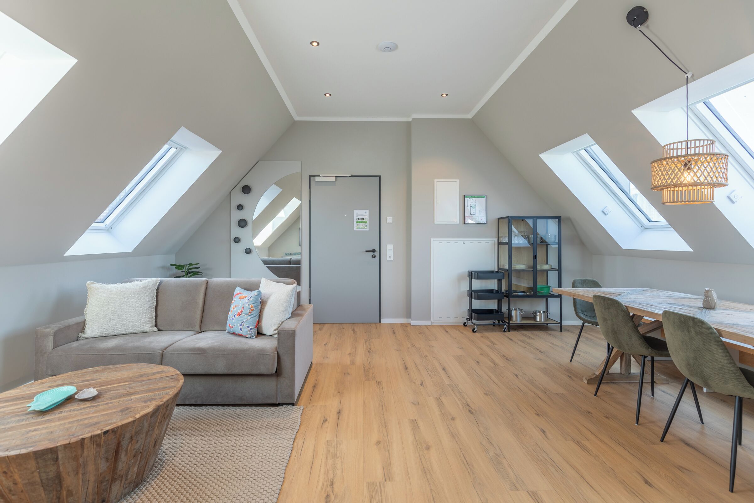 A spacious loft apartment with high ceilings, skylights, a dining area, and a cozy seating area.