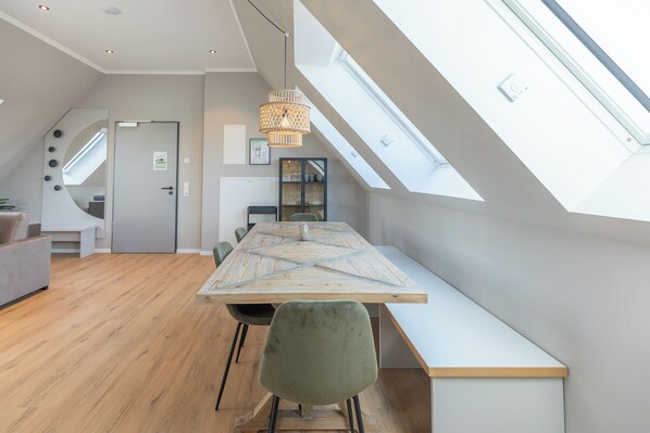 A modern loft with a high ceiling, skylight, and a dining area with a long table and chairs. - Apartment at the old customs office (Deluxe) directly at Husum harbor (Husum)