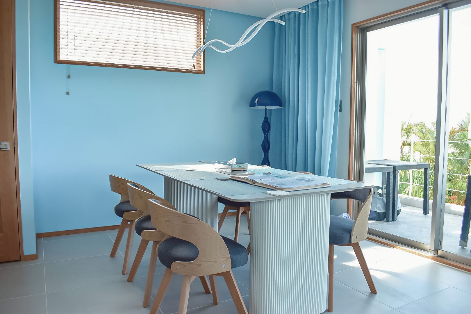 A modern dining area with a table, chairs, and a view of the outdoors.