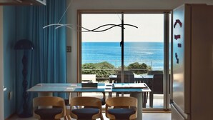 A dining area with a table and chairs, a view of the sea, and a large window. - Ocean View Ishigaki Kaze & Nami (Ishigaki)