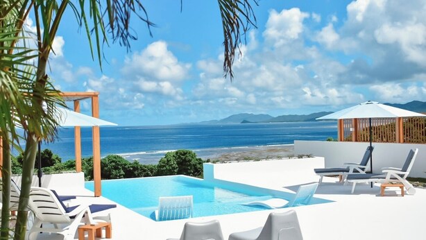 A pool area with lounge chairs and a view of the sea. - Ocean View Ishigaki Kaze & Nami (Ishigaki)