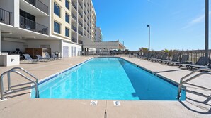 A swimming pool with lounge chairs and a building with balconies. - Island Winds West 471 (Gulf Shores)