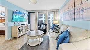 A living room with a television, sofa, and a ceiling fan. - Island Winds West 471 (Gulf Shores)