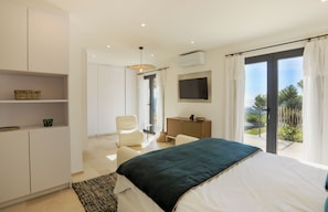 Relax in this serene bedroom with a large bed, flat-screen TV, and a balcony offering a view of the outdoors.