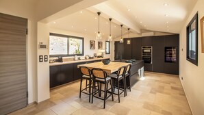 Una cocina moderna con una isla grande, armarios oscuros e iluminación colgante.