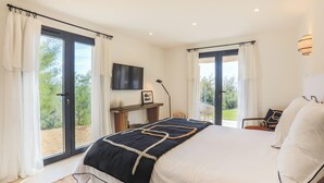 Un dormitorio moderno con una cama grande, un televisor de pantalla plana y vistas al balcón.