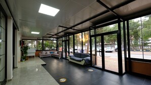 Un vestíbulo amplio con zona de estar, ventanas grandes y piso de baldosas.