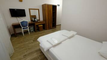 Habitación de hotel con cama, escritorio con silla, televisor y armario.