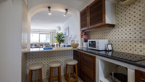 Een keuken met een centraal eiland, houten krukken, een magnetron en een raam met uitzicht.