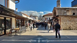 Eine Fußgängerzone mit Geschäften und Cafés, im Hintergrund ein Gebäude mit einem Glockenturm.