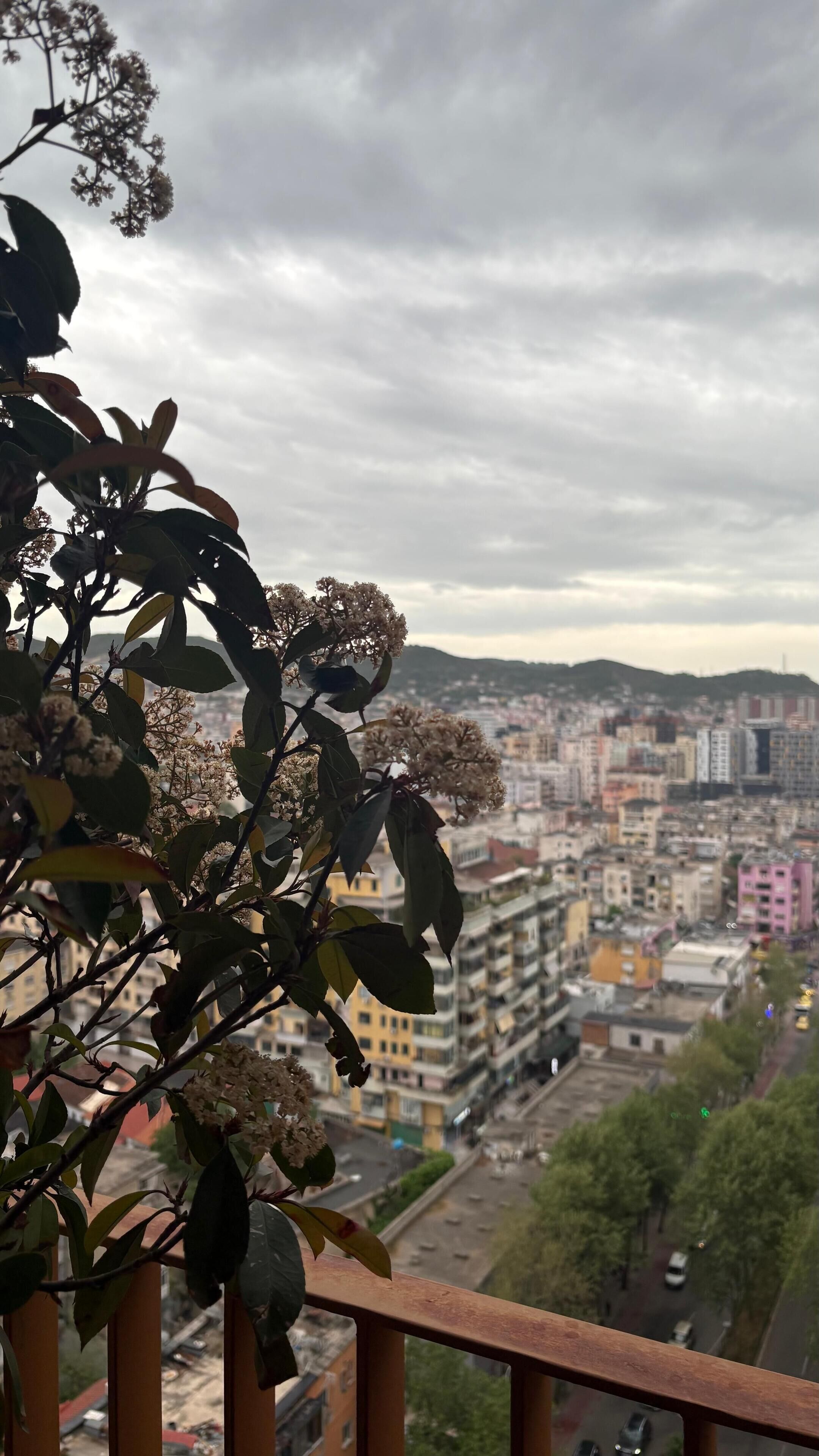 Ein Balkon mit Blick auf eine Stadtansicht, einschließlich Gebäude und einer entfernten Hügelkette.