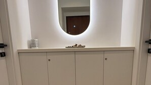 A hallway with a welcome mat, a mirror, and a cabinet.
