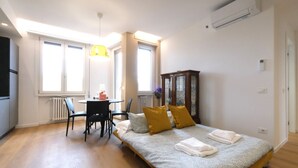 Une chambre à coucher avec un lit, un bureau et une chaise. On y trouve une fenêtre, un radiateur et un placard.