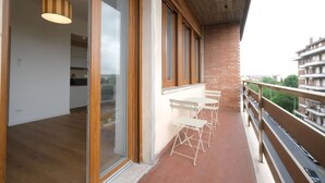 Un balcon donnant sur une vue de la ville, un plancher en bois et un luminaire suspendu.
