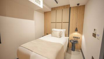 A modern hotel room with a bed, bedside table, and a small desk with a telephone.