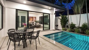 A modern outdoor pool area with a dining set and a sliding glass door leading to a living room. - Villa Elima, lovely pool two bedrooms villa at rawai (rawai)