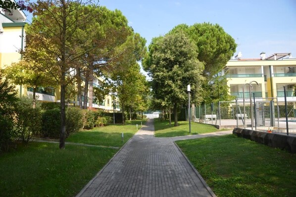 A pathway leading through a park-like setting with trees and a building in the background.
