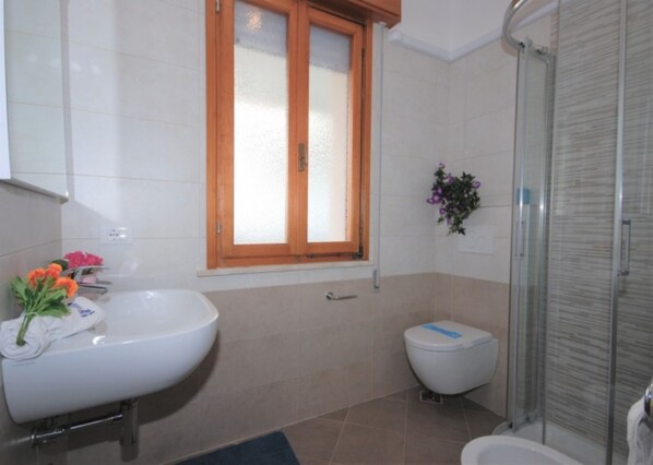 Un baño con lavamanos, inodoro y ducha.