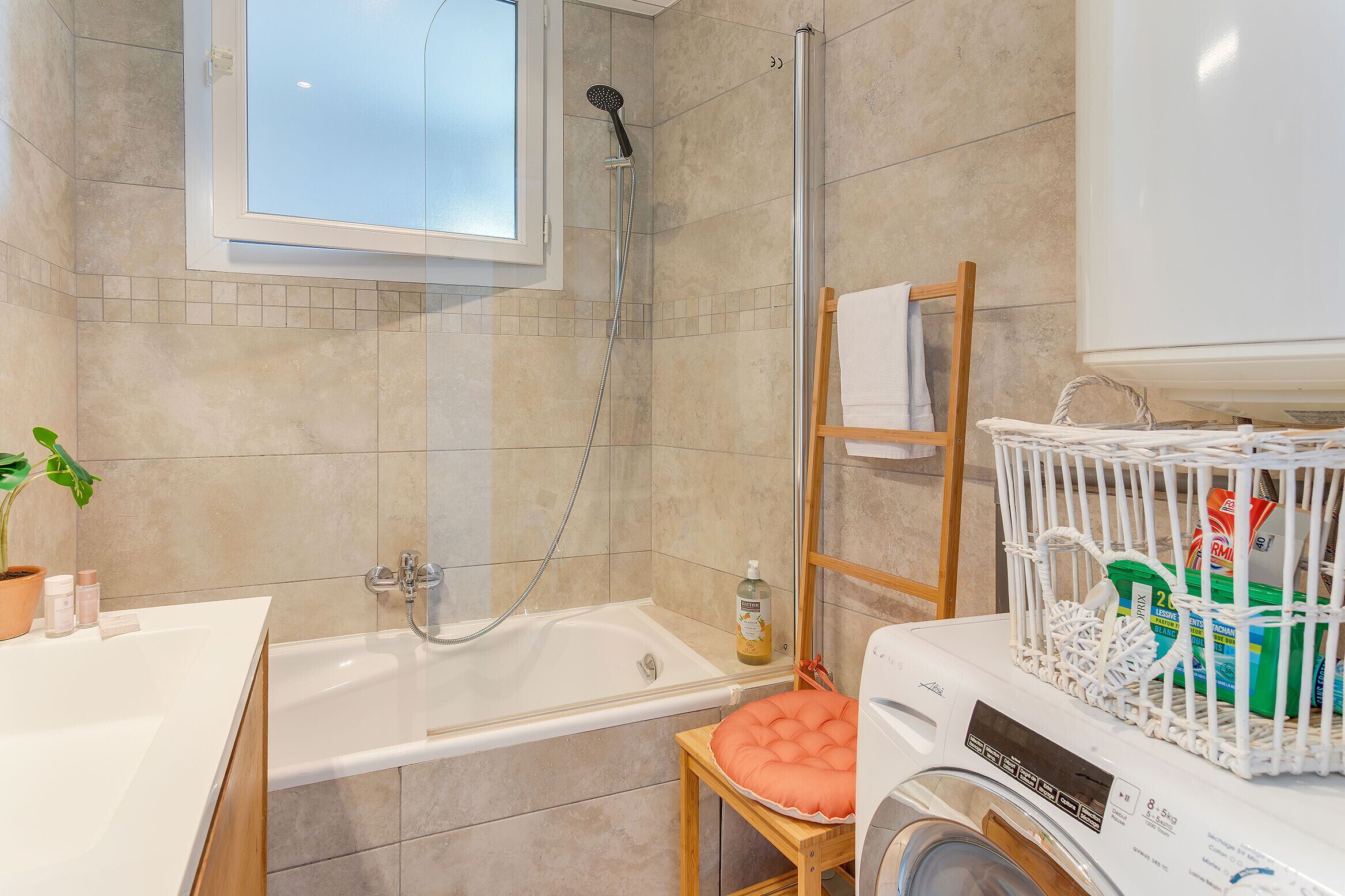 A bathroom with a bathtub, shower, and a washing machine.
