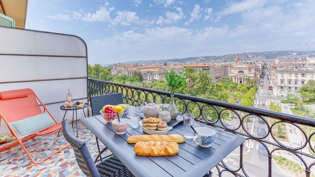 Un balcon avec une table mise pour le petit-déjeuner, comprenant du pain et des viennoiseries, ainsi qu’une chaise.
