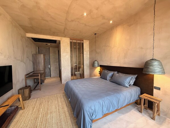 A modern bedroom with a large bed, a TV, and a wooden bench. - inchantreedoolay Huahin (Pranburi)