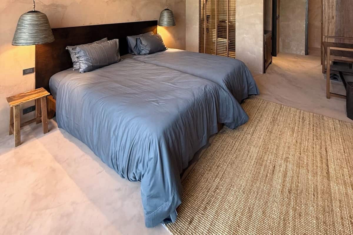 Une chambre à coucher avec un grand lit, deux lampes de chevet, une table de chevet en bois et un tapis tissé.