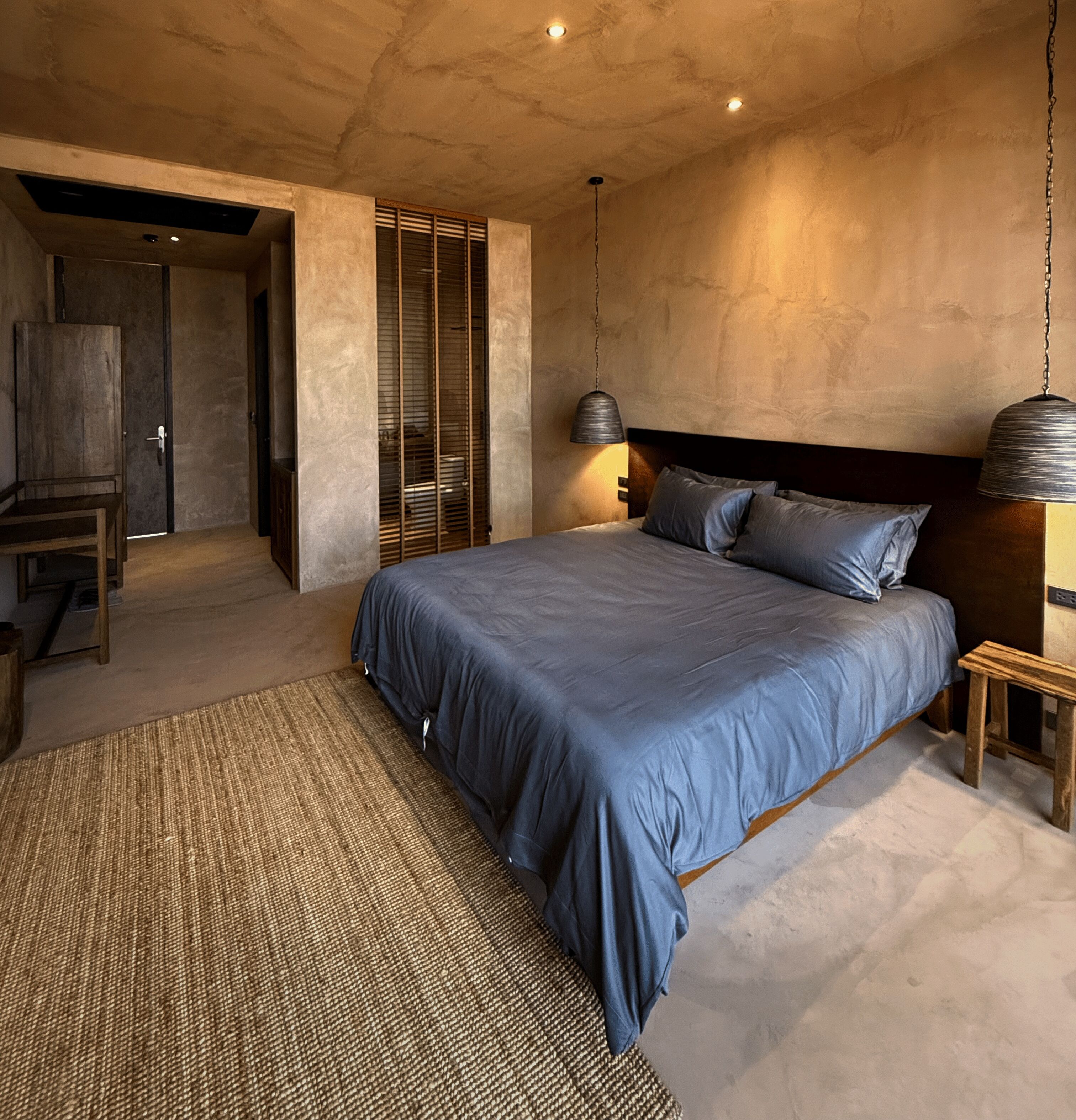 A bedroom with a large bed, a wooden nightstand, a hanging lamp, and a wardrobe.