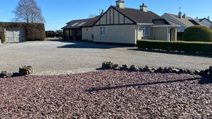 A residential property with a gravel driveway, a stone wall, and a well-maintained hedge.