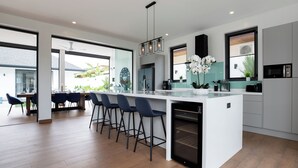 A modern kitchen with a central island, bar stools, and a dining area with chairs.