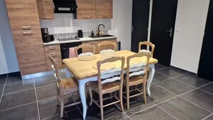 Moderni keittiö, jossa on puiset kaapit, musta liesituuletin ja laatoitettu välitila.