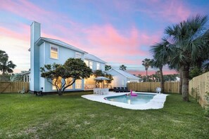 Une maison avec un jardin, une piscine et des palmiers.