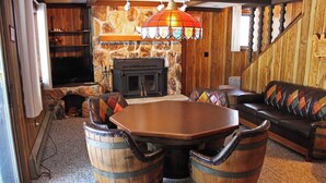 A cozy living room with a stone fireplace, wooden furniture, and a unique hanging light fixture. - A Large Trailside Vacation Home with 2 Large Fireplaces (Ironwood)