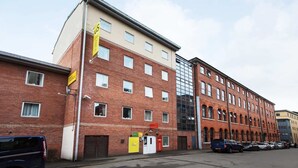 En byggnad med flera våningar, vars fasad består av en kombination av tegel och glas, och som har flera fönster samt en tydligt markerad entré.