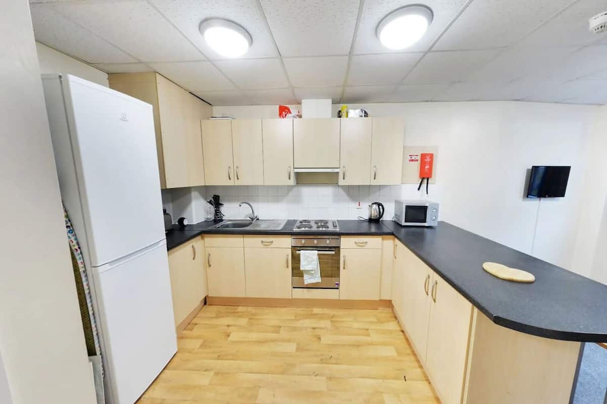 A compact kitchen with a refrigerator, stove, microwave, and sink.