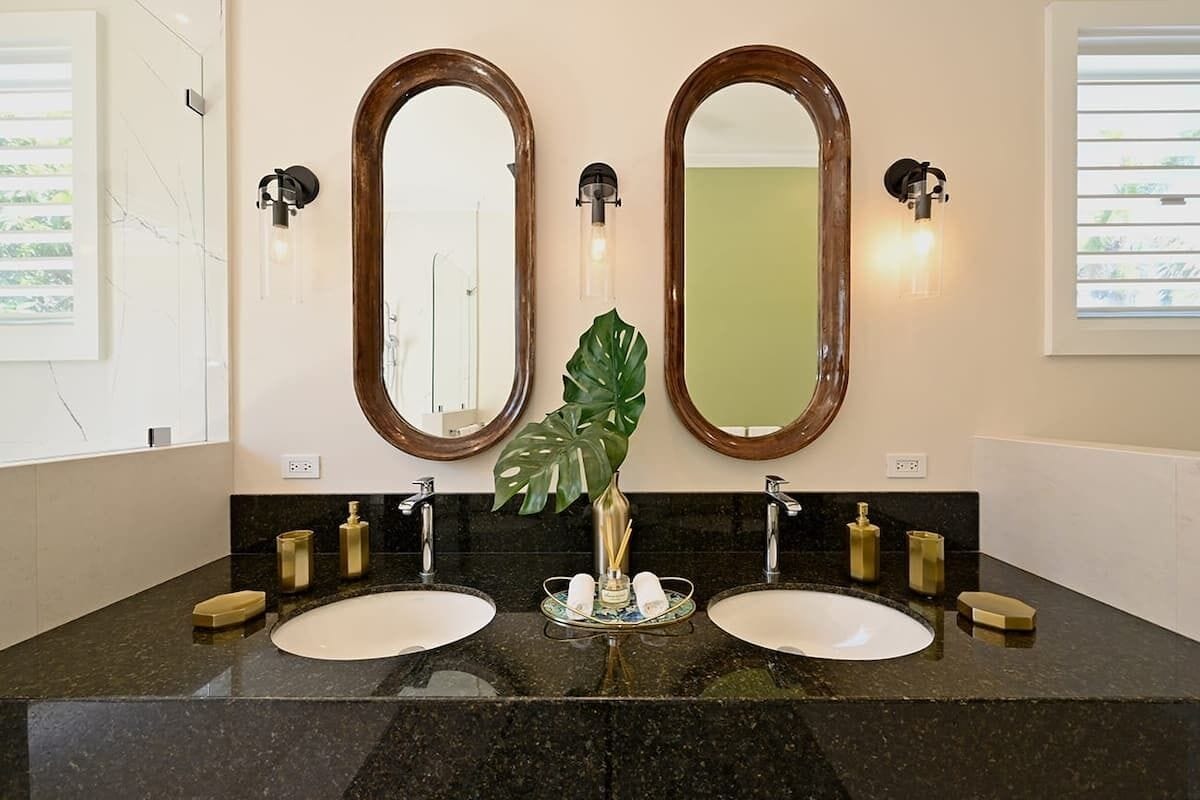 Un baño con dos lavamanos, un espejo grande y una planta en el centro.