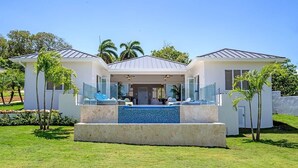 Una casa moderna con piscina, dos casas de huéspedes y un césped bien cuidado.